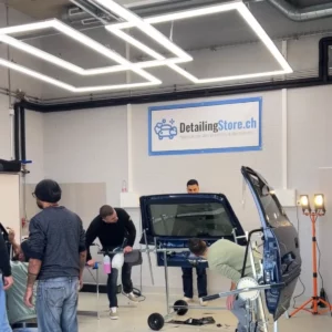 Vue d'ensemble de l'atelier avec plusieurs stagiaires travaillant sur des éléments de vitrage.