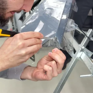 Gros plan sur la découpe au cutter d'un film protecteur sur carrosserie.