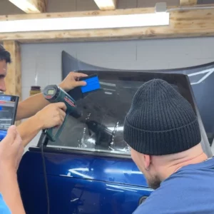 Utilisation d'un décapeur thermique pour thermoformer un film solaire sur une lunette arrière.